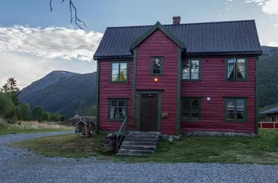 a red house with mountains in the background at Maristuen Fjellferie in Borgund