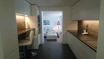 a kitchen with a counter and a room with a bed at Peak Apartments in Vossevangen