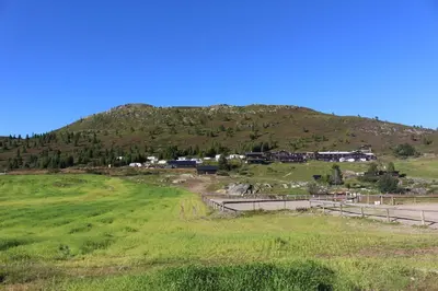 a green hill with houses on the side of a road at Sulseter Fjellstugu in Vinstra