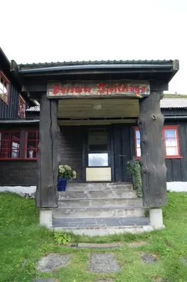 a building with a door and stairs in the grass at Sulseter Fjellstugu in Vinstra