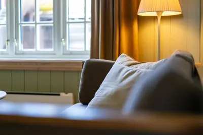 a couch with a pillow in a room with a lamp at Ilsetra Hotell in Hafjell