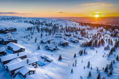 a snow covered village in the mountains with the sun setting at Ilsetra Hotell in Hafjell