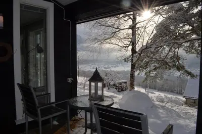 a porch with a table and chairs in the snow at Klara House in Isfjorden