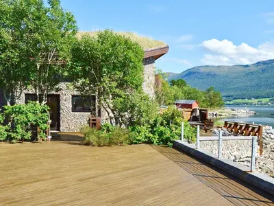 a building with a wooden deck next to a lake at 10 person holiday home in EIDSVÅG-By Traum in Rød