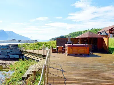 a wooden deck with a building and a boat on it at 6 person holiday home in EIDSVÅG-By Traum in Rød