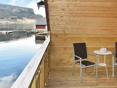a table and chairs on a wooden deck with water at 6 person holiday home in Leirvik i Sogn-By Traum in Bø