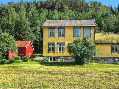 a yellow house and a red barn in a field at 8 person holiday home in Liabygda-By Traum in Eidsdal