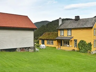 a yellow house with a grass yard next to two buildings at 8 person holiday home in Liabygda-By Traum in Eidsdal