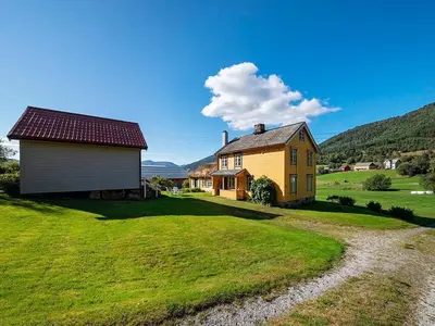a yellow house on a green field next to a house at 8 person holiday home in Liabygda-By Traum in Eidsdal