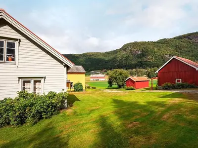 a house and a barn with a mountain in the background at 8 person holiday home in Liabygda-By Traum in Eidsdal