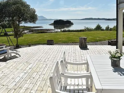 a patio with two white chairs and a table and water at 10 person holiday home in Tornes I Romsdal in Tornes