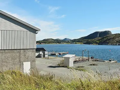 a building next to a body of water with a dock at 12 person holiday home in Oksvoll in Oksvoll