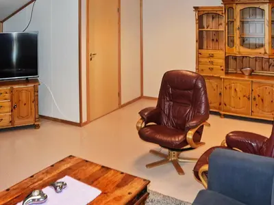 a living room with a leather chair and a table at 12 person holiday home in Oksvoll in Oksvoll