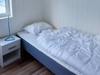 an unmade bed in a small room with a night stand at 8 person holiday home in Oksvoll in Oksvoll