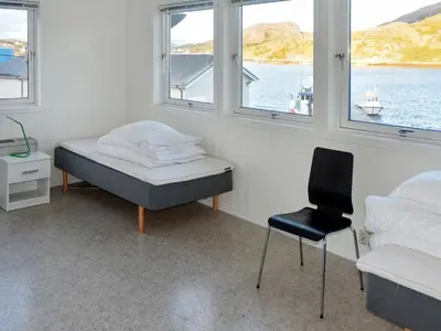 a bedroom with a bed and a chair and windows at 8 person holiday home in Oksvoll in Oksvoll