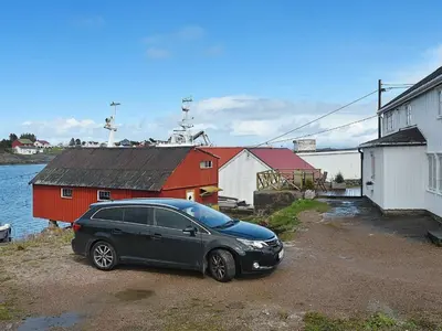 a black car parked in front of a red building at 8 person holiday home in averøy in Henda