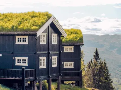 a black house with a grass roof on a hill at 10 person holiday home in Fåvang in Strande