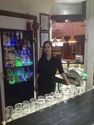 a woman standing in front of a bar with wine glasses at VIKEDAL VERTSHUS hotel in Vikedal