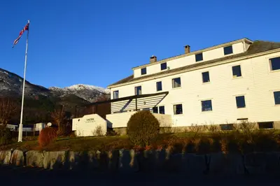 a white building with a flag in front of it at VIKEDAL VERTSHUS hotel in Vikedal