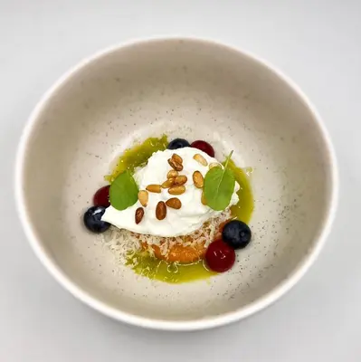 a white bowl with a dessert with fruit and whipped cream at Blåtind Boutique Hotel in Stordal