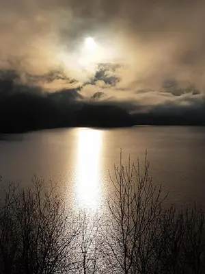 a sunset over a body of water with the sun shining at Vikinghaug in Odda