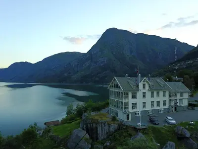 a large white house on the edge of a lake at Vikinghaug in Odda