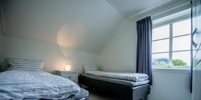 a bedroom with a bed and a chair and a window at Viken Holiday Home in Viksdalen