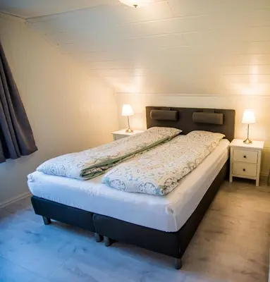 a bed in a room with two lamps on two tables at Viken Holiday Home in Viksdalen