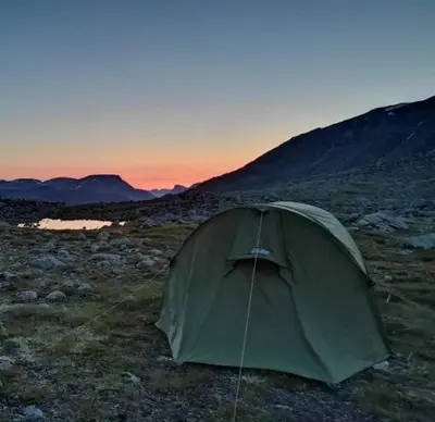 a green tent in a field with mountains in the background at Kjøsnes Feriehytter in Skei