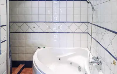 a bath tub in a bathroom with white tiles at Gorgeous Home In Matre With Wifi in Hamre