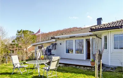 a white house with a table and chairs in the yard at 2 Bedroom Gorgeous Home In Sveio in Sveio
