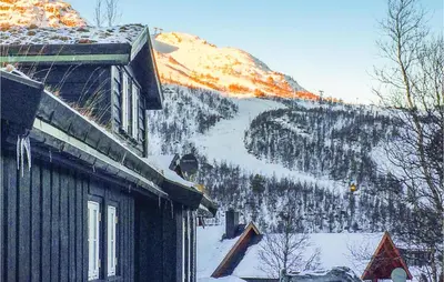 a house with a snow covered mountain in the background at Pet Friendly Home In Hovden With Sauna in Hovden