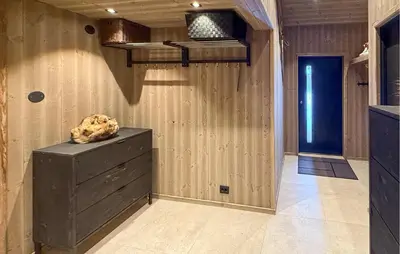 a room with a wooden wall with a dresser and a shelf at Nice Home In Hovden With Sauna in Hovden