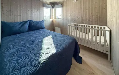 a bedroom with a blue bed and a crib at Nice Home In Hovden With Sauna in Hovden