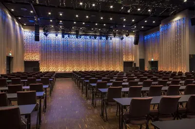 a large room with tables and chairs and a stage at Scandic Flesland Airport in Bergen