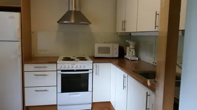 a kitchen with white cabinets and a stove and a microwave at HI Borlaug Vandrerhjem in Borgund