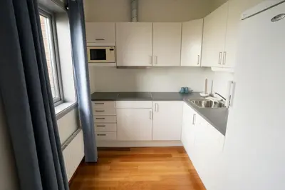 a small kitchen with white cabinets and a sink at Bjugn Hotell in Botngard