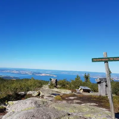 a sign on top of a mountain with the ocean in the background at Idylliske Evjua ved Mjøsa in Skreia