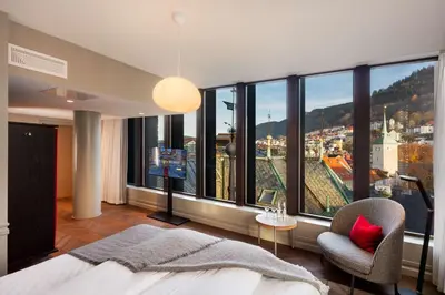 a bedroom with a large window with a bed and a chair at Bergen Børs Hotel in Bergen
