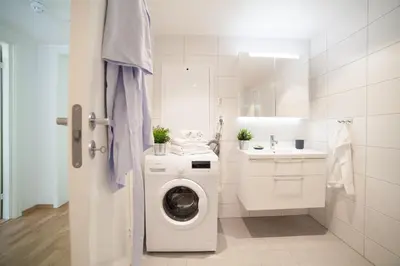 a white bathroom with a washing machine and a sink at BJØRVIKA APARTMENTS, Damsgård Area, Bergen city center in Bergen