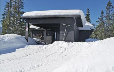 a building covered in snow with a pile of snow at 3 Bedroom Stunning Home In Sjusjøen in Sjusjøen