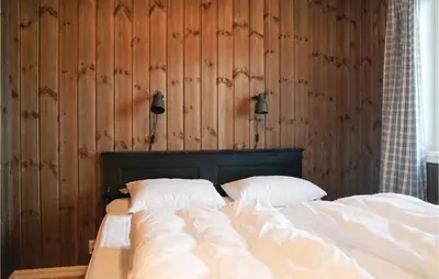 a bedroom with two beds and wooden walls at Sjusjøen Setergrend 4763 in Sjusjøen