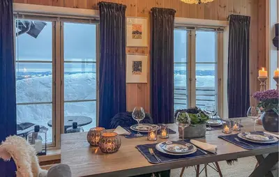 a dining room table with a view of the snow at Cozy Home In Sjusjøen With Sauna in Sjusjøen