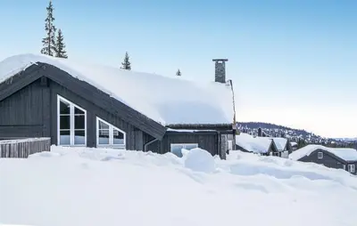 a house covered in snow with a pile of snow at Cozy Home In Sjusjøen With Sauna in Sjusjøen