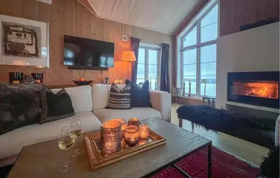 a living room with a couch and a table with wine glasses at Cozy Home In Sjusjøen With Sauna in Sjusjøen