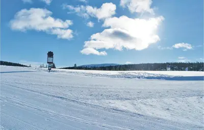a snow covered field with a lighthouse in the distance at Three-Bedroom Holiday Home In Sjusjoen in Sjusjøen