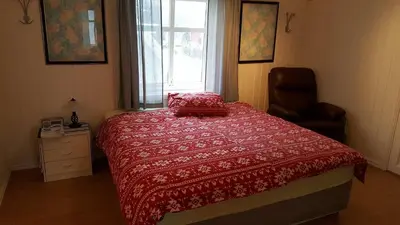 a bedroom with a bed with a red comforter and a window at Egil's Vacation House in Lillehammer