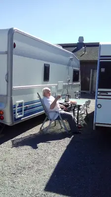 a woman sitting in a chair next to a trailer at Sæteråsen Hytter & Camping Trysil in Trysil