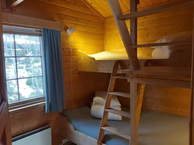 a room with a bunk bed and a ladder in a log cabin at Magalaupe Camping in Oppdal