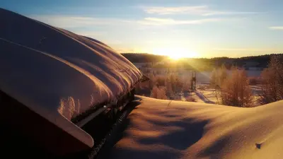 a view of the sun setting over a snow covered field at Gamlestølen Fjellstue in Etnedal
